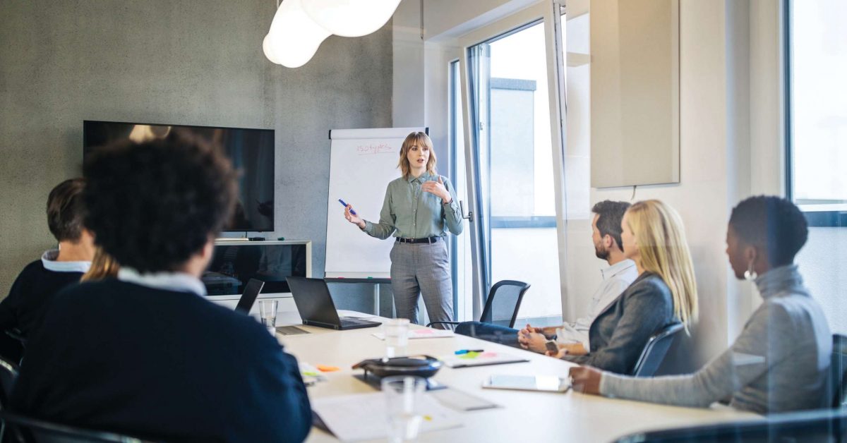 Businesswoman addressing a meeting around board table. Group of business people having board meeting in modern office.