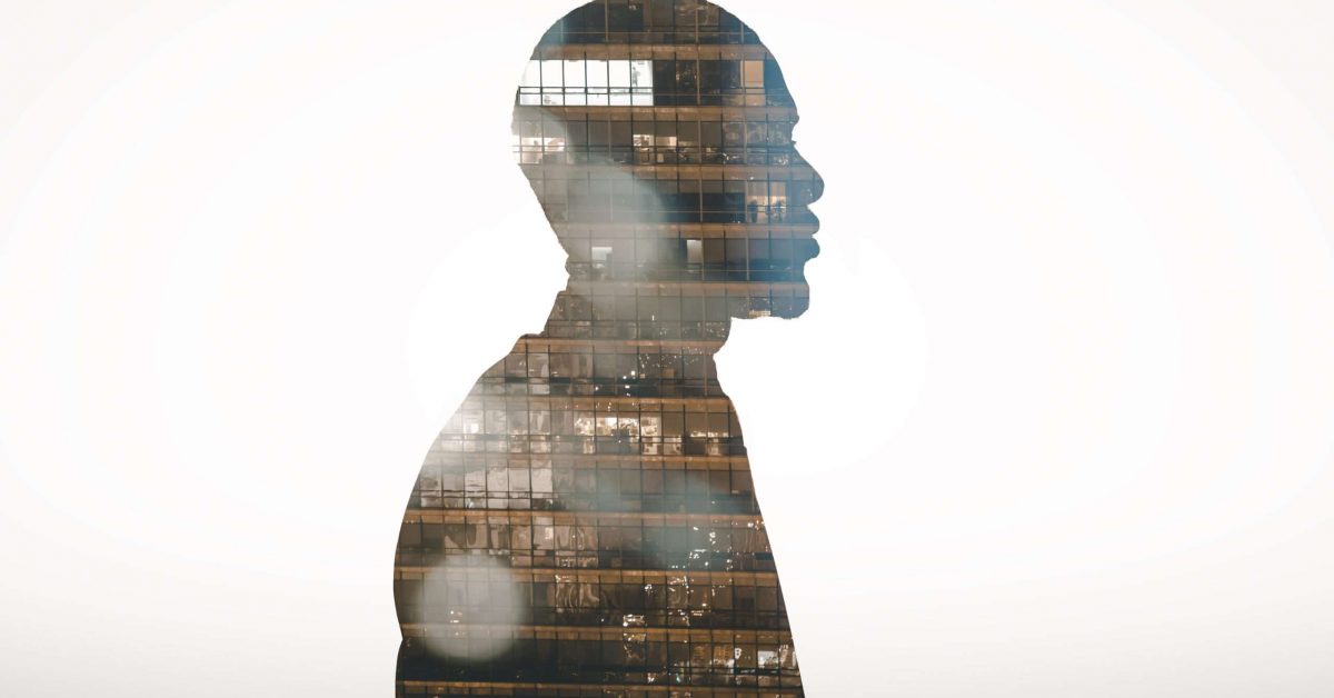 Profile view silhouette of businessman double exposed with city at night