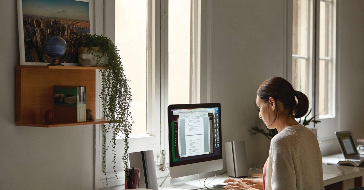 Female professional using computer at table. Woman is working from home during coronavirus lockdown period. She is wearing casual.