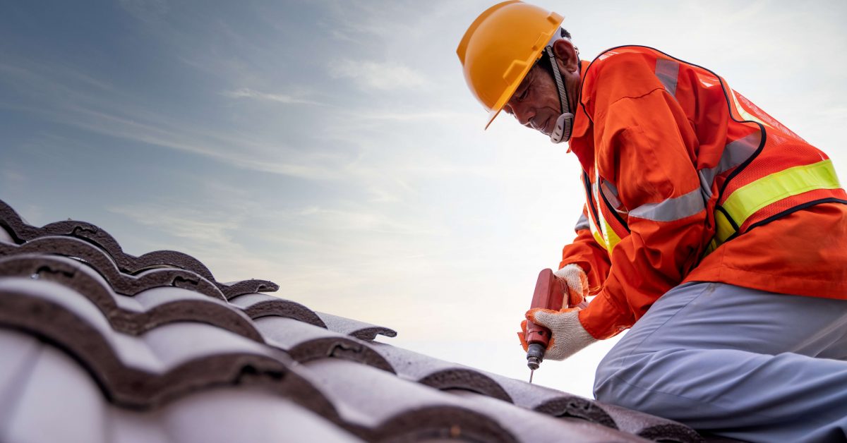 Construction worker install new roof, Electric drill used on new roofs with tiled roof