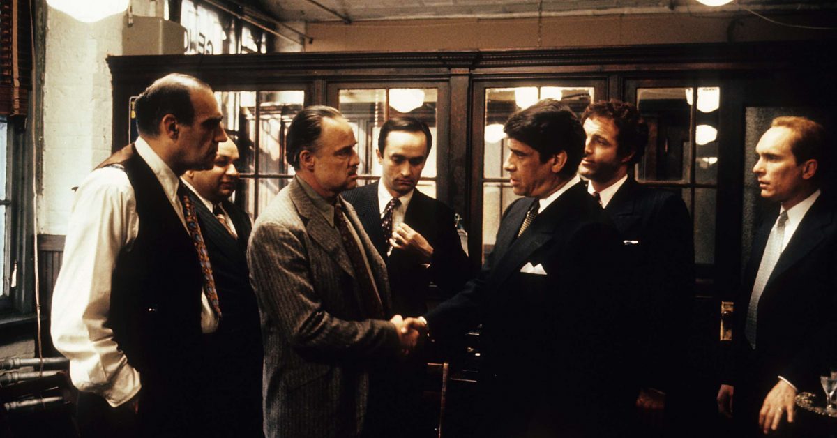 Abe Vigoda and Robert Duvall watch Marlon Brando and Al Lettieri shake hands in a scene from the film 'The Godfather', 1972. (Photo by Paramount/Getty Images)