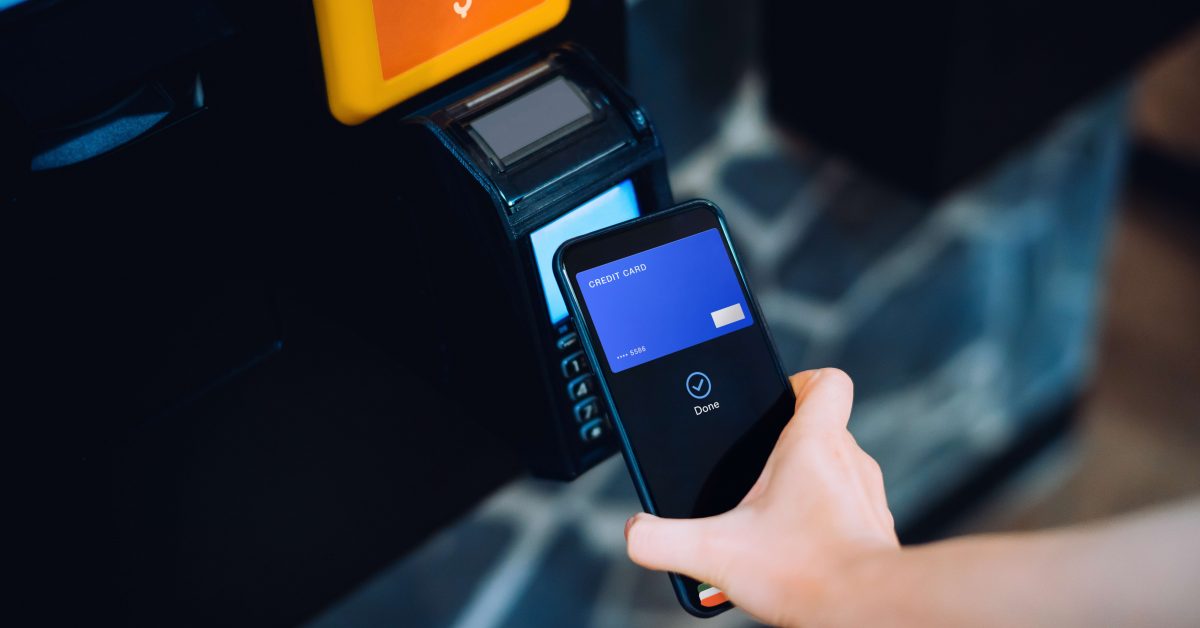 Close up of a woman's hand paying with her smartphone on a vending machine, scan and pay a bill on a card machine making a quick and easy contactless payment. NFC technology, tap and go concept