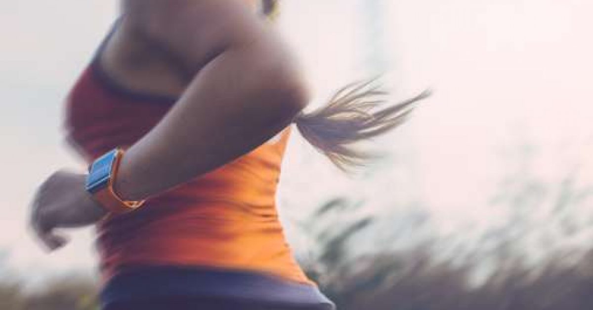 Woman running outdoor using a smart watch to track data.